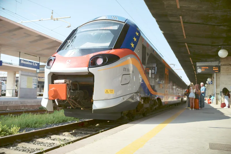 Treno in partenza dal binario di una stazione luminosa